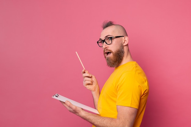 Free photo young bearded employee man casual wear taking notes against a pink background