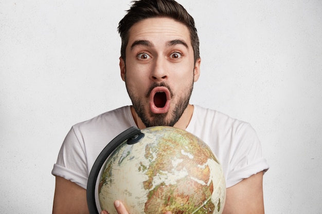 Free photo young bearded man with globe