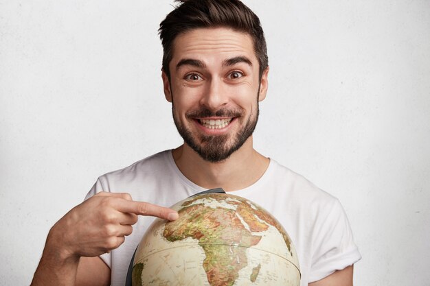 Free photo young bearded man with globe