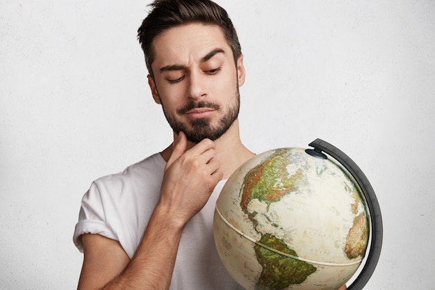 Free photo young bearded man with white t-shirt and globe