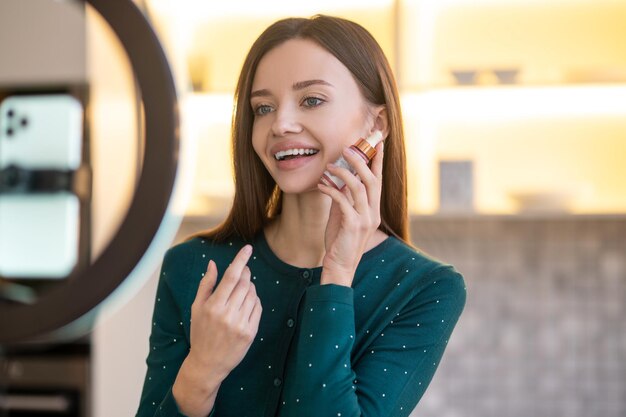 Young beautician demonstrating new beauty products during online workshop