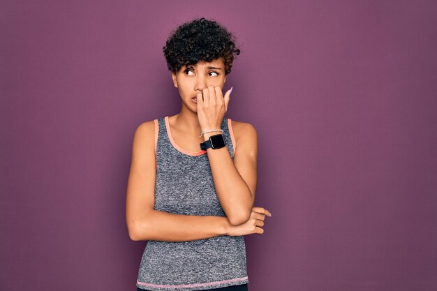 Young beautiful african american afro sportswoman doing exercise wearing sportswear looking stressed and nervous with hands on mouth biting nails Anxiety problem