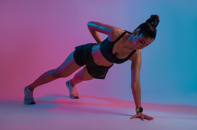 Young beautiful Asian woman with athletic body doing push ups at modern fitness center