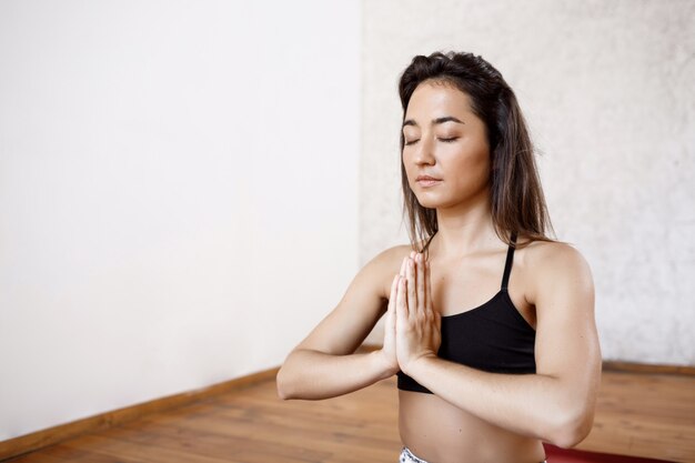 Young beautiful athletic woman practicing indoor yoga on red mat