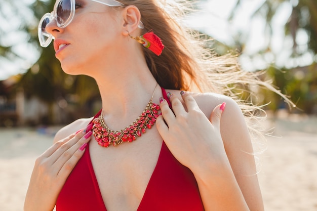 Free Photo young beautiful blond woman sunbathing on beach in red swimming suit, sunglasses