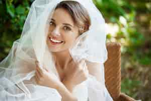 Free photo young beautiful blonde bride in wedding dress and veil smiling.