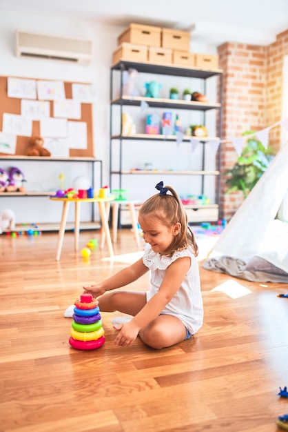 Free photo young beautiful blonde girl kid enjoying play school with toys at kindergarten smiling happy playing with inteligence toys at home