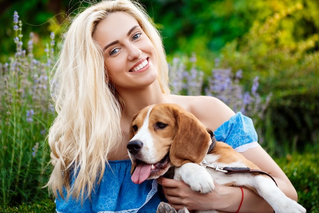 Free photo young beautiful blonde girl walking, playing with beagle dog in park.