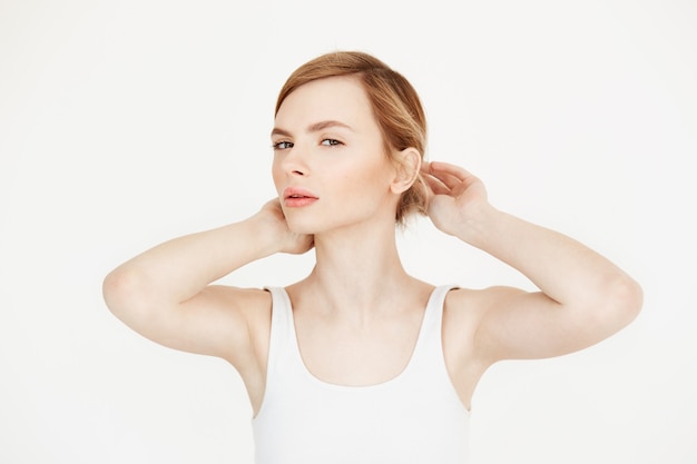 Young beautiful blonde girl with clean fresh skin sitting at table  correcting hairstyle. Beauty and spa.