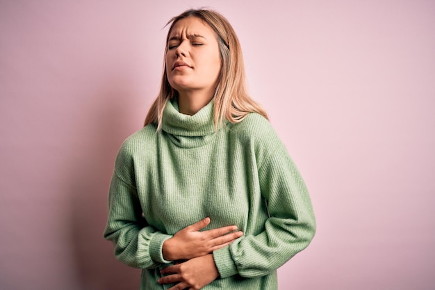 Free photo young beautiful blonde woman wearing winter wool sweater over pink isolated background with hand on stomach because nausea painful disease feeling unwell ache concept