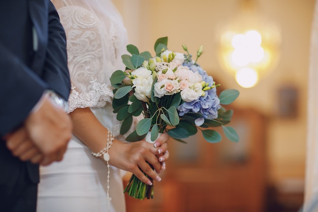 A young and beautiful bride is standing with her husband in a church