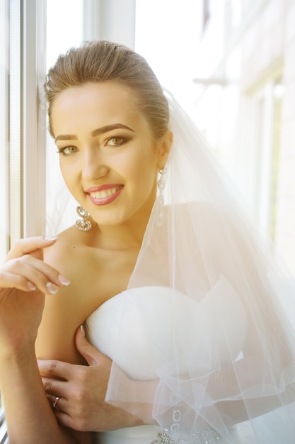 Free photo young beautiful bride posing against the window in the hotel room