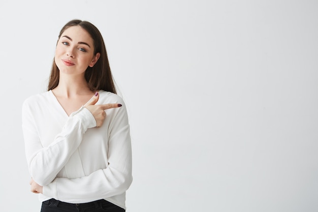 Young beautiful brunette businesswoman smiling pointing finger in side .