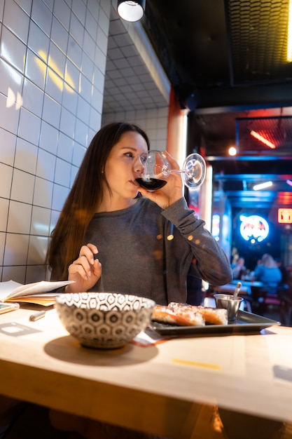 Young beautiful brunette drinks wine in a cafe