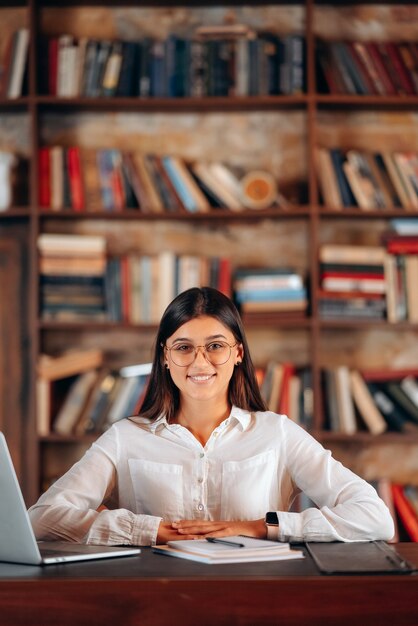 Free Photo young beautiful business woman in glasses sits at a work table