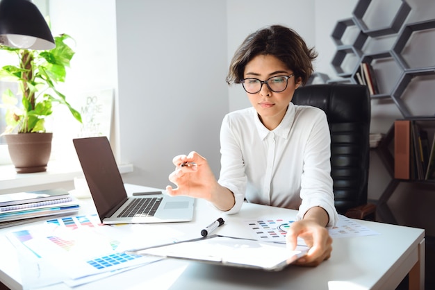 Young beautiful businesswoman sitting at workplace in office.