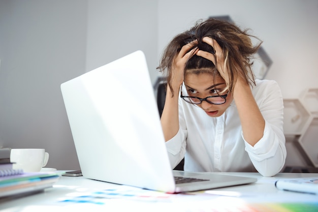 Free photo young beautiful businesswoman working with laptop at workplace in office.