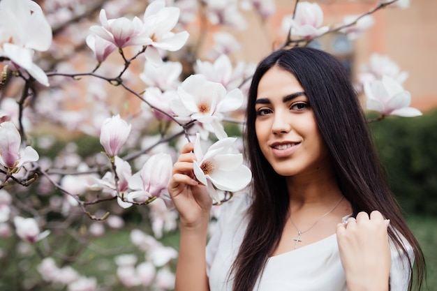 Young beautiful caucasian girl in a blossoming spring magnolia garden. The girl in the garden morning. Portrait, close-up.