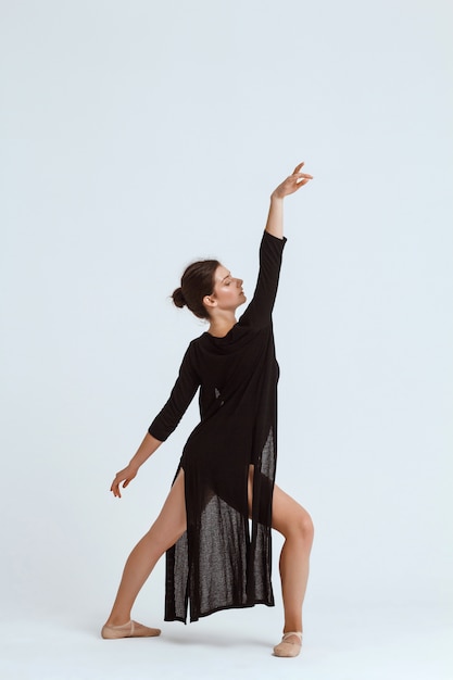 Free photo young beautiful contemporary dancer posing over white wall. copy space.