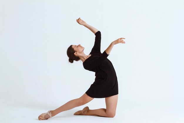 Young beautiful contemporary dancer posing over white wall. Copy space.