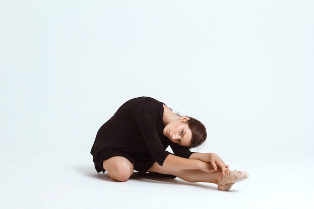 Free photo young beautiful contemporary dancer posing over white wall. copy space.