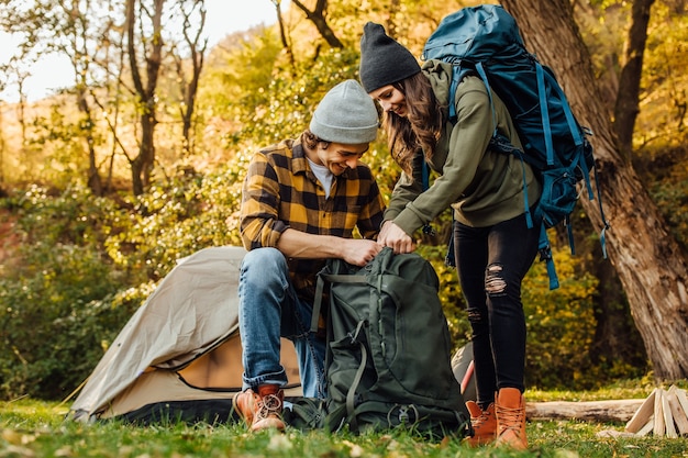 Free photo young beautiful couple gather their backpacks on a hike