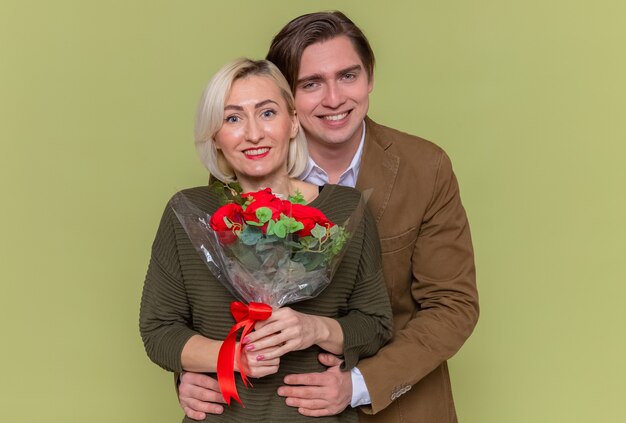 Young beautiful couple happy man with bouquet of red roses and woman