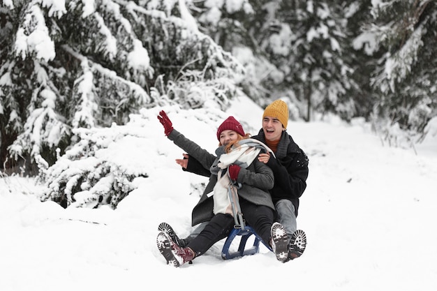 Young beautiful couple having fun on the sleigh