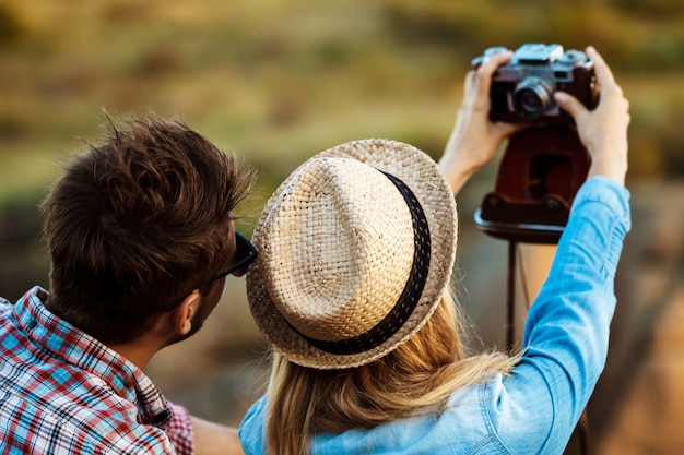 Free photo young beautiful couple making selfie on old camera, canyon background