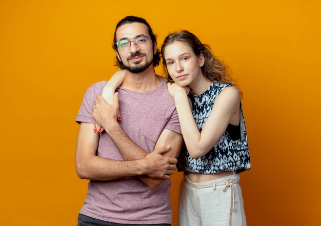 young beautiful couple man and women happy in love  standing over orange wall