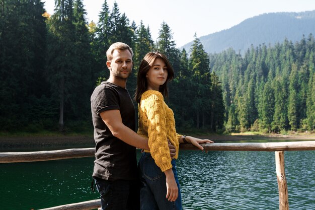 Young beautiful couple smiling, embracing, lake and mountains