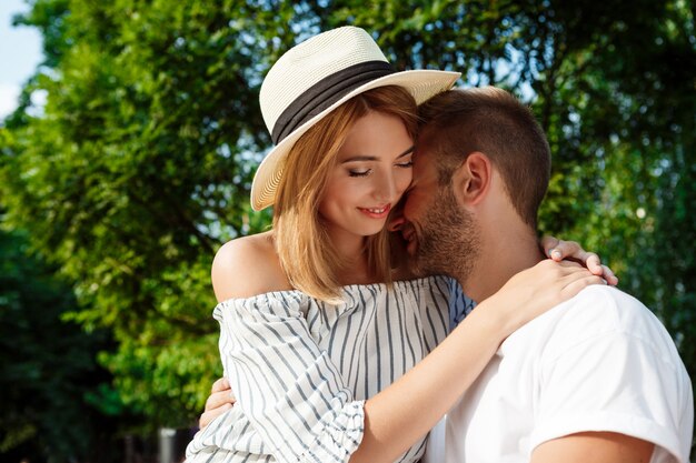 Young beautiful couple smiling, embracing, walking in park.