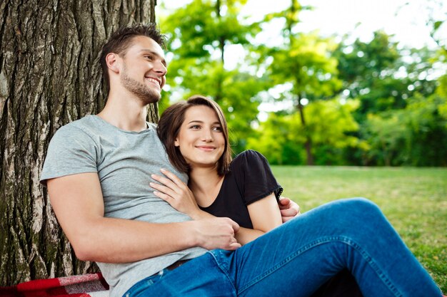 Young beautiful couple smiling, resting on picnic in park.