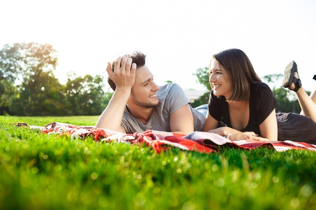 Free photo young beautiful couple smiling, resting on picnic in park.