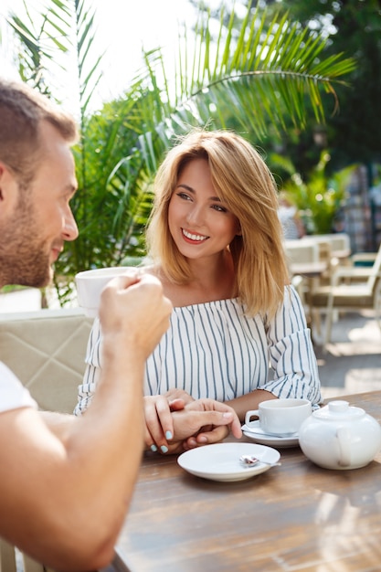 Young beautiful couple speaking, smiling, resting in cafe.