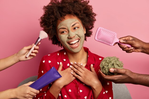 Young beautiful curly woman dressed in sleepwear, smiles sincerely, looks aside