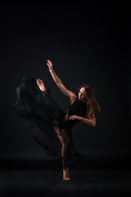 Free Photo young beautiful dancer in beige dress dancing on black wall