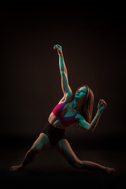 Young beautiful dancer in beige dress dancing on black