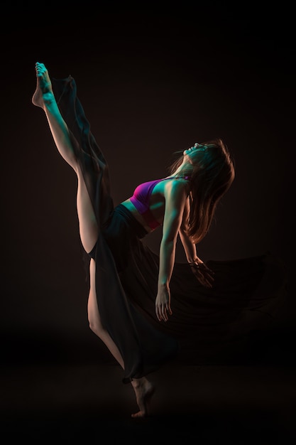 Young beautiful dancer in beige dress dancing on black