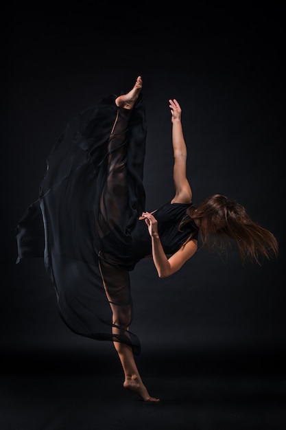 Young beautiful dancer in beige dress dancing on black