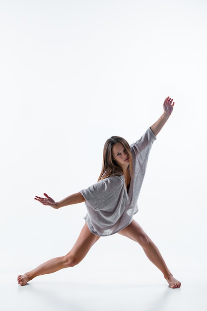 Young beautiful dancer in beige dress dancing on white