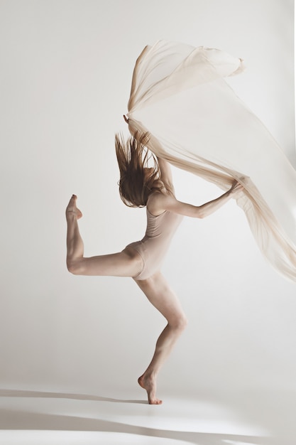 Young beautiful dancer in beige swimsuit dancing