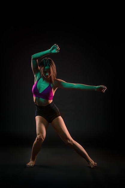 Young beautiful dancer dancing on black