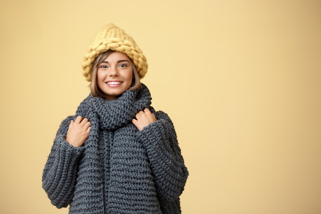 Free Photo young beautiful fair-haired woman in knited hat and sweater smiling on yellow.