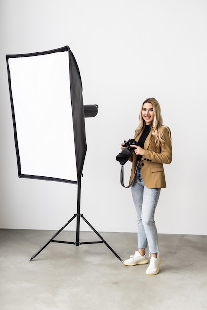 Free photo young beautiful female posing for a photo shoot in a studio a photographer is shooting with a digital camera