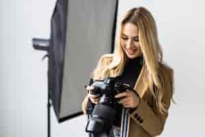 Free photo young beautiful female posing for a photo shoot in a studio a photographer is shooting with a digital camera