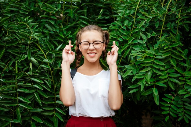 Young beautiful female student in glasses hoping, posing over leaves outdoors.