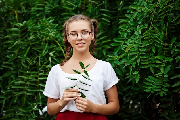 Free Photo young beautiful female student in glasses smiling, posing over leaves outdoors.