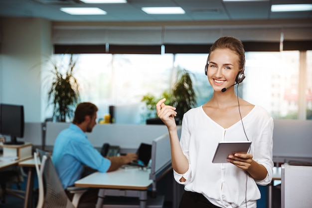 Young beautiful female support phone operator speaking, consulting, over office