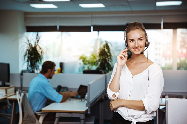 Young beautiful female support phone operator speaking, consulting, over office